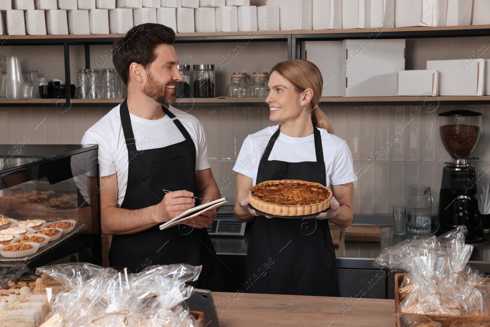 Photo of Sellers with notebook and freshly baked quiche in bakery shop