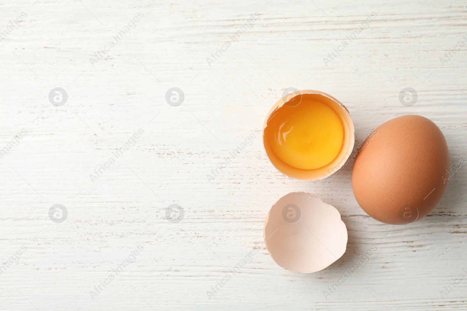 Photo of Raw chicken eggs on wooden background, top view. Space for text