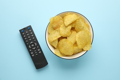 Photo of Remote control and bowl of potato chips on light blue background, flat lay