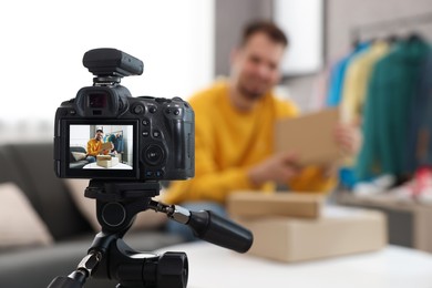 Photo of Fashion blogger with parcels recording video at home, focus on camera