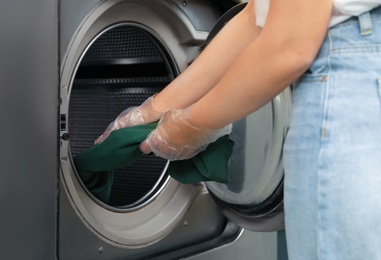 Photo of Young woman unloading washing machine in dry-cleaning, closeup