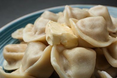 Photo of Tasty dumplings with butter on blue plate, closeup