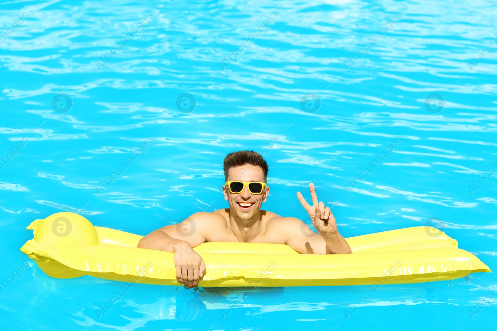 Photo of Happy young man with inflatable mattress in swimming pool