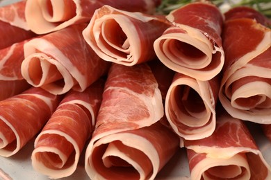Photo of Rolled slices of delicious jamon on plate, closeup
