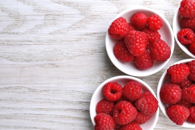 Photo of Tasty ripe raspberries on white wooden table, flat lay. Space for text