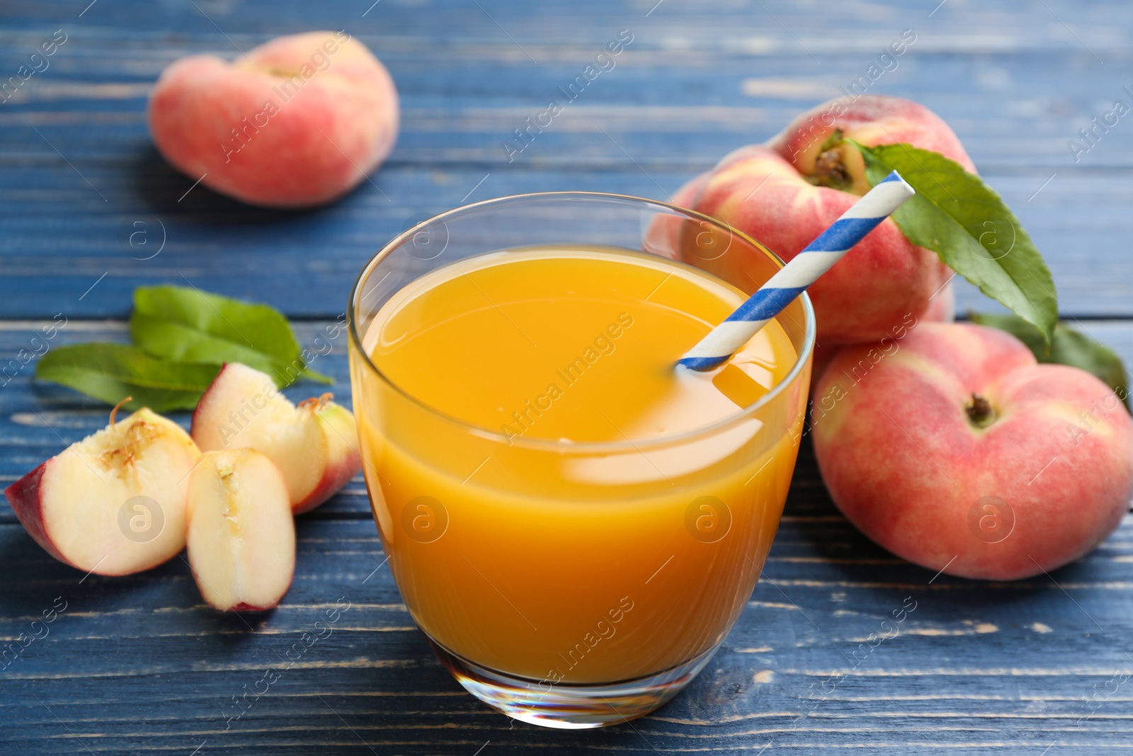 Photo of Natural peach juice and fresh fruits on blue wooden table, closeup