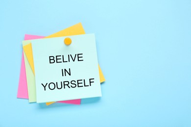 Photo of Notes with phrase Believe In Yourself on light blue background, top view. Motivational quote