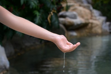 Photo of Kid pouring water from hand in pond, closeup