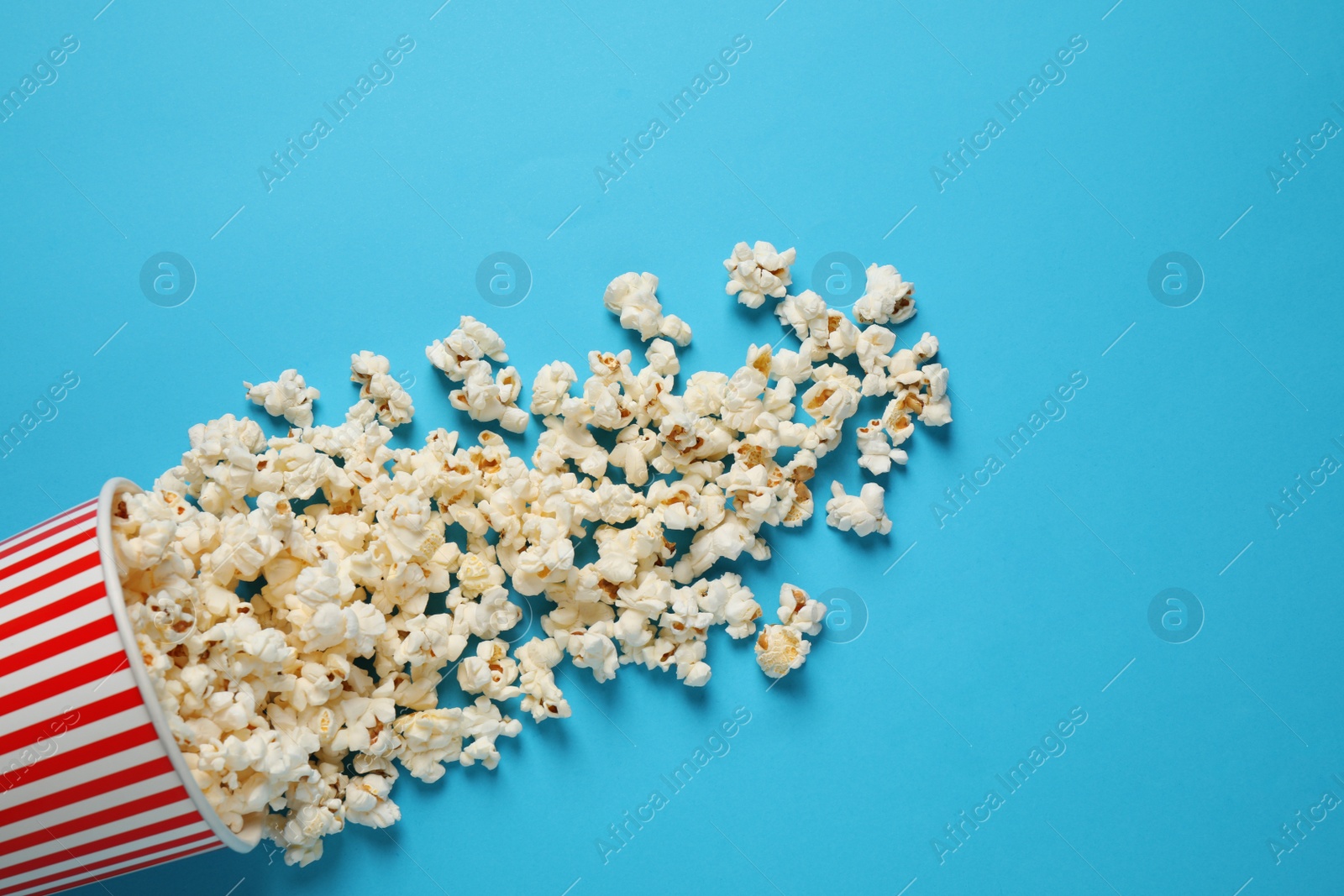 Photo of Delicious popcorn on light blue background, top view