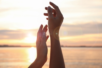 Young woman enjoying beautiful sunset near river, closeup. Nature healing power