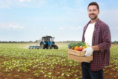 Harvesting season. Farmer holding wooden crate with crop in field