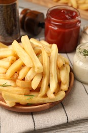 Delicious french fries served with sauces on light wooden table, closeup