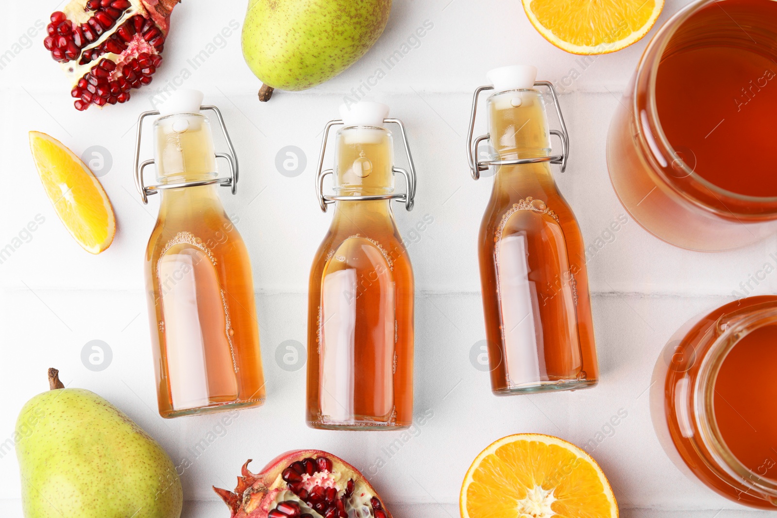 Photo of Tasty kombucha and fresh fruits on white tiled table, flat lay