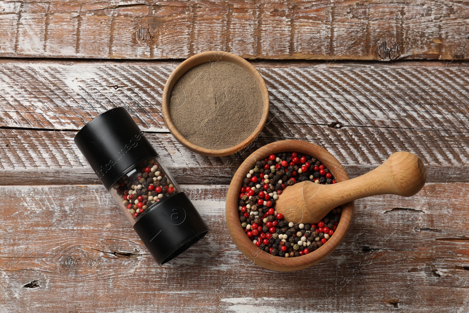 Photo of Ground pepper and grains on wooden table, flat lay