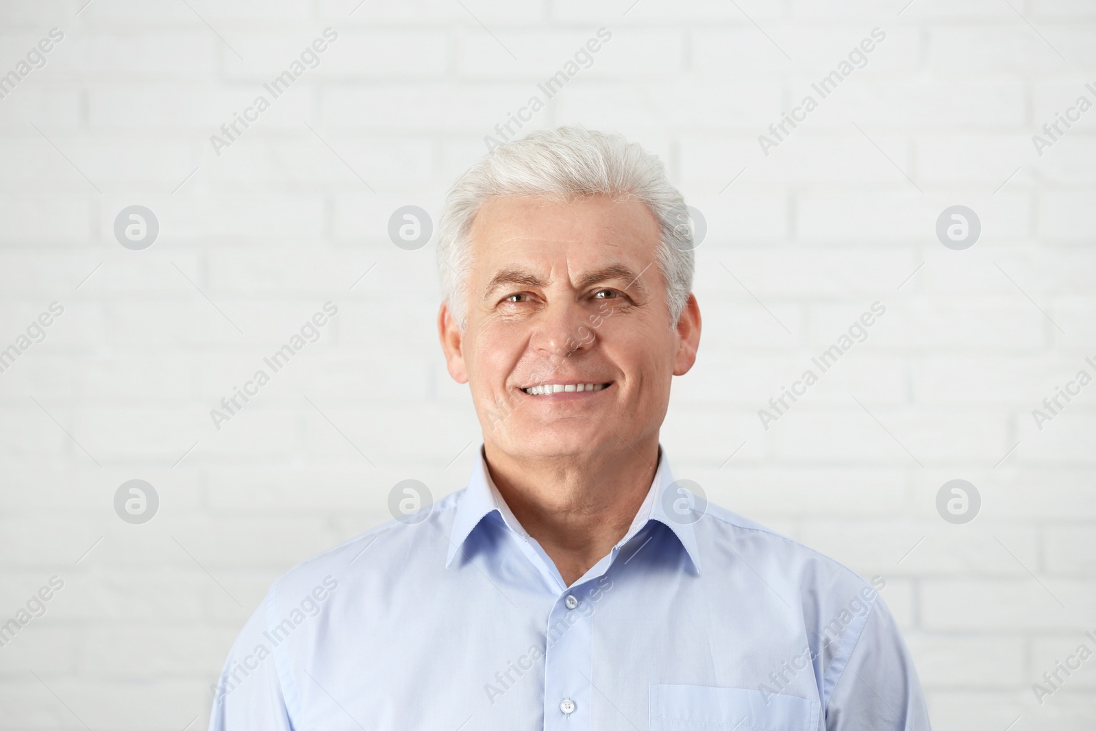 Photo of Portrait of handsome mature man near brick wall