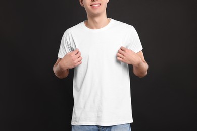 Man wearing white t-shirt on black background, closeup. Mockup for design