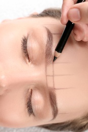 Photo of Young woman having eyebrow correction procedure in beauty salon, closeup