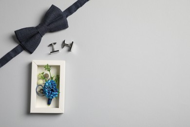 Photo of Wedding stuff. Stylish boutonniere, bow tie and cufflinks on gray background, flat lay. Space for text
