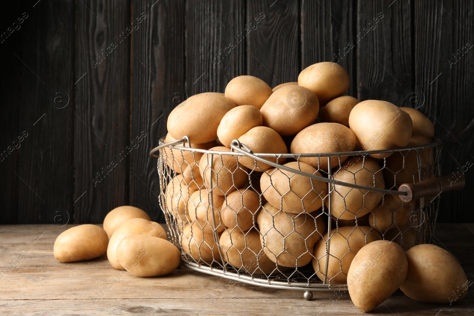 Photo of Raw fresh organic potatoes on wooden table against dark background