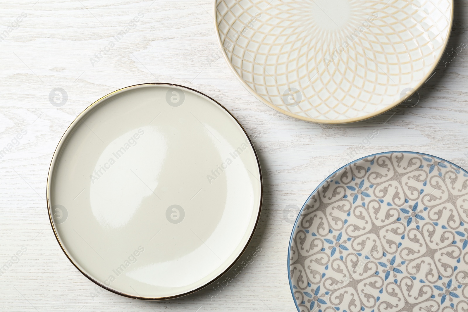 Photo of Three beautiful plates on white wooden table, flat lay