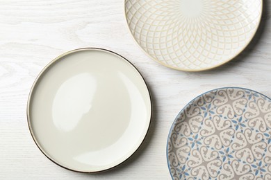 Photo of Three beautiful plates on white wooden table, flat lay