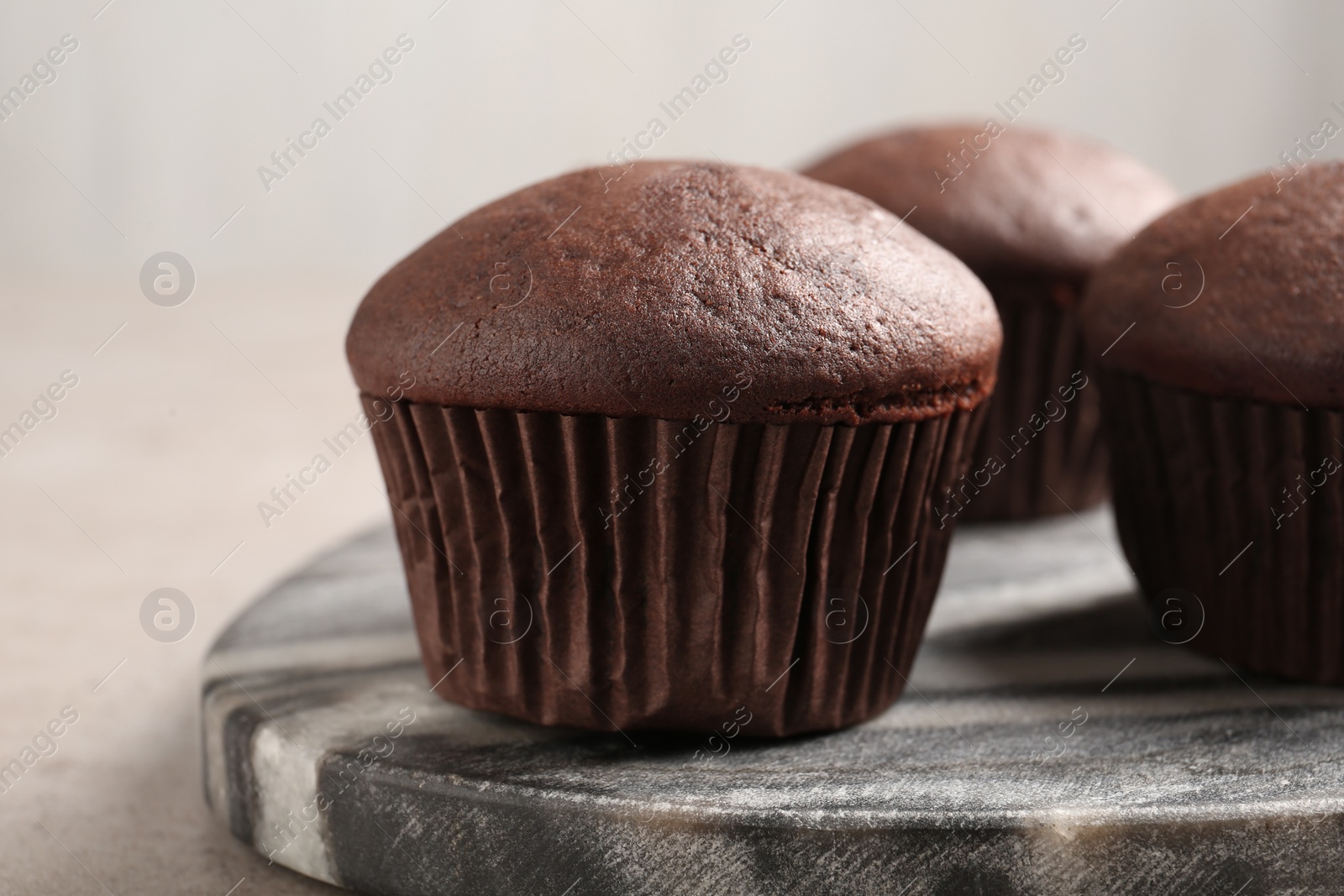 Photo of Delicious fresh chocolate cupcakes on grey marble board, closeup