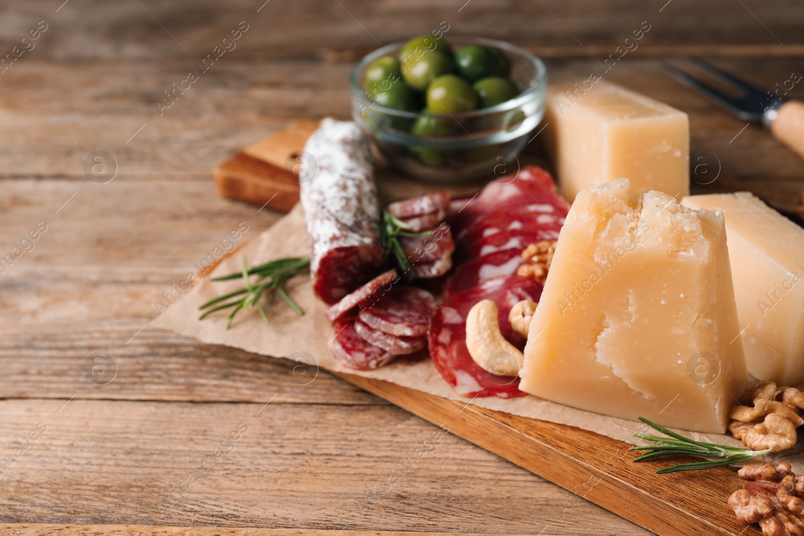 Photo of Snack platter with parmesan cheese on wooden table, closeup. Space for text