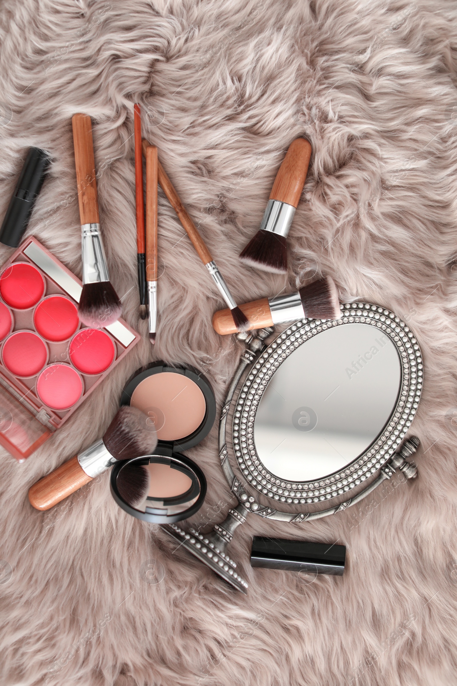 Photo of Flat lay composition with makeup brushes, cosmetic products and mirror on faux fur