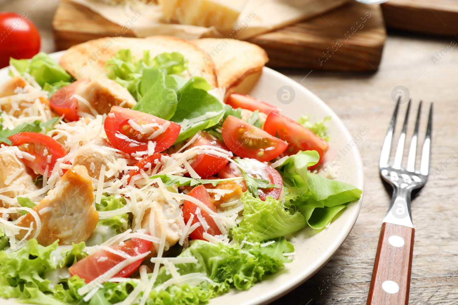 Photo of Delicious fresh Caesar salad on wooden table, closeup