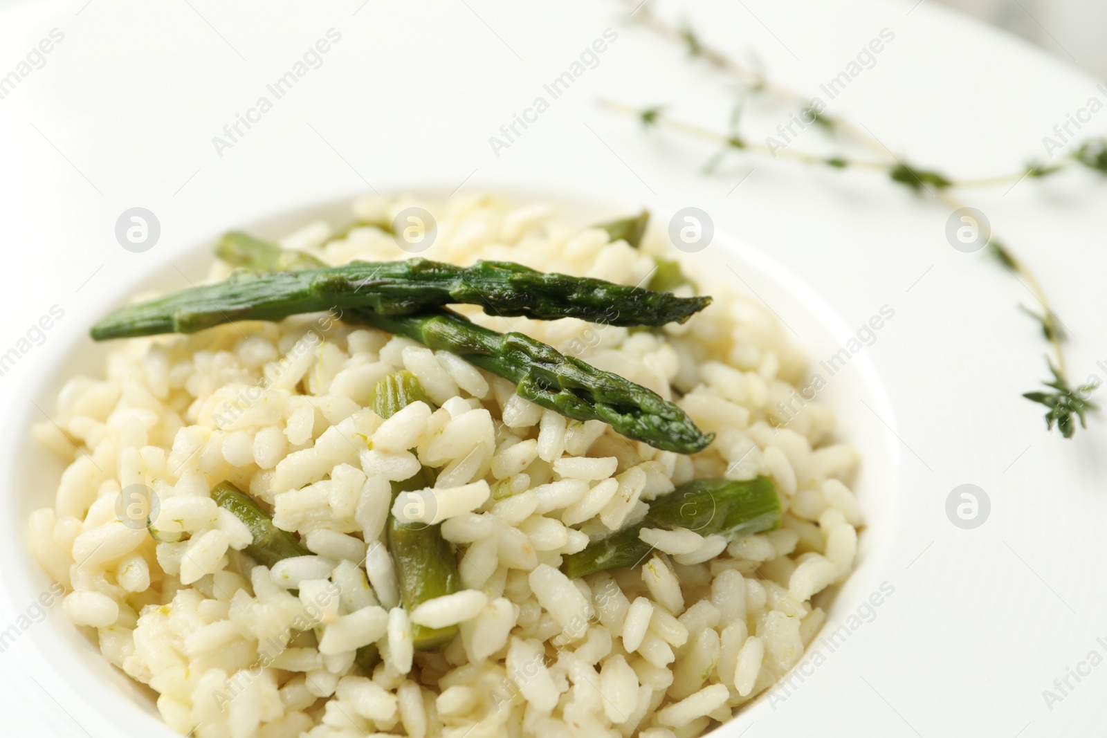 Photo of Delicious risotto with asparagus in plate, closeup