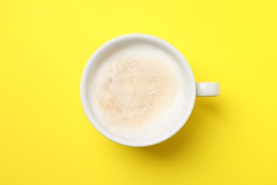 Photo of Aromatic coffee in cup on yellow background, top view