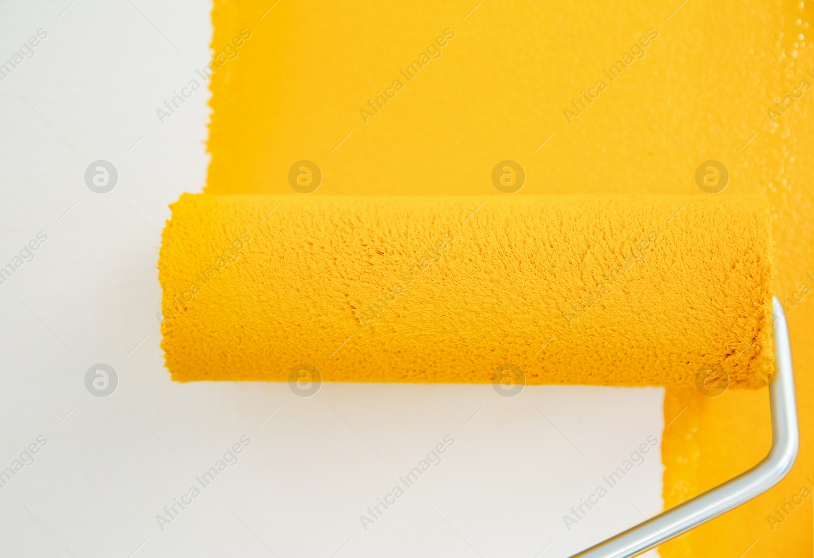 Photo of Painting white wall with yellow dye, closeup. Interior renovation