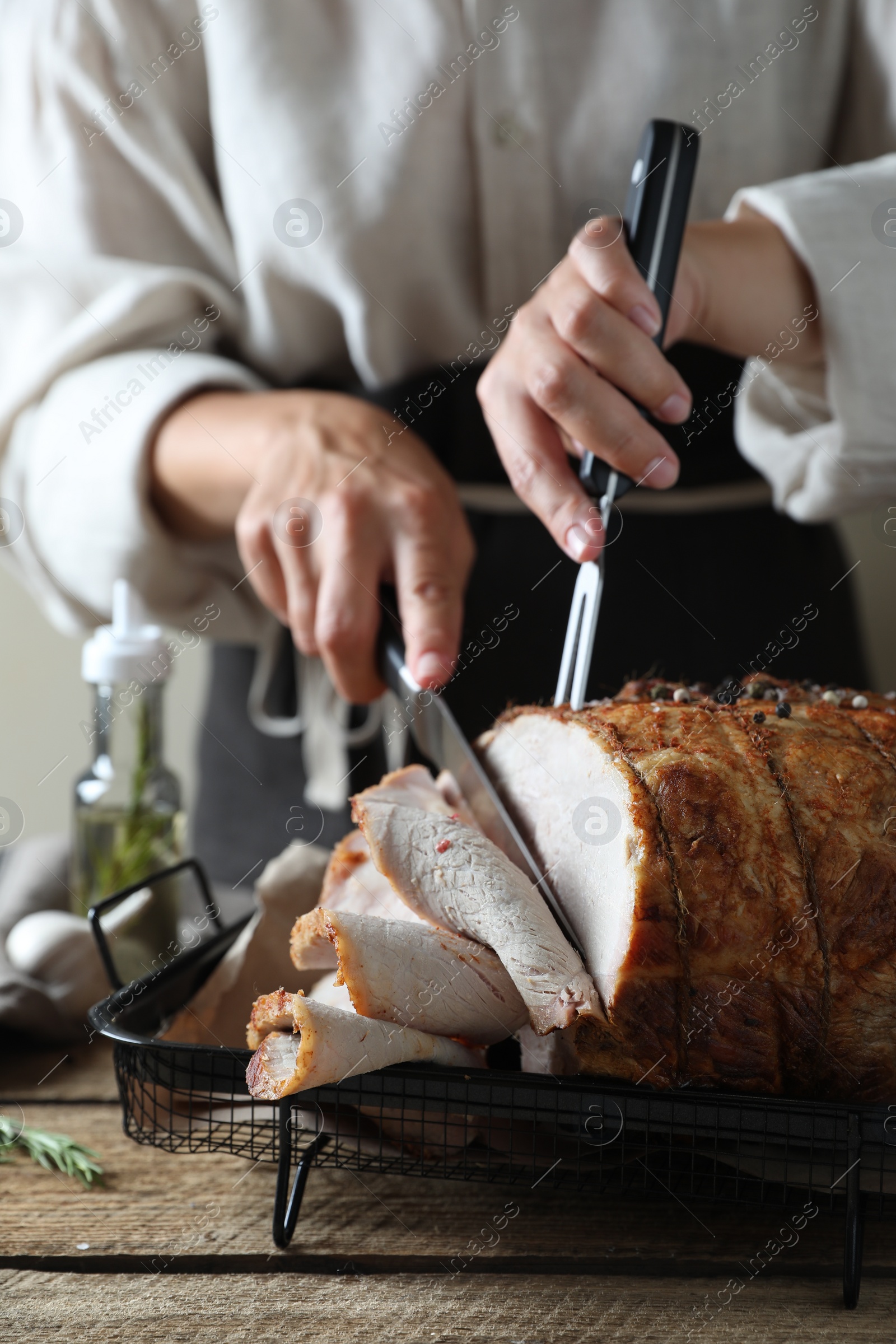 Photo of Woman cutting delicious baked ham at wooden table, closeup