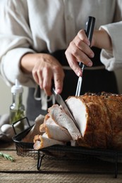 Photo of Woman cutting delicious baked ham at wooden table, closeup