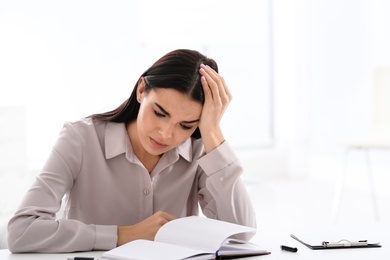 Stressed young woman at table in office