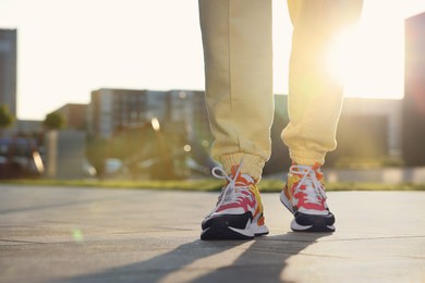 Woman walking in stylish sneakers outdoors, closeup. Space for text