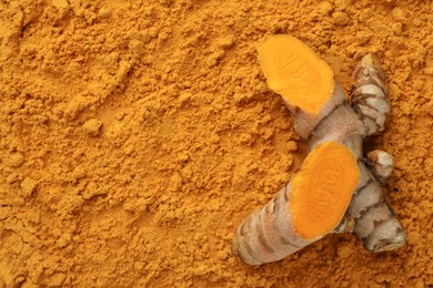 Photo of Cut raw root on aromatic turmeric powder, top view. Space for text