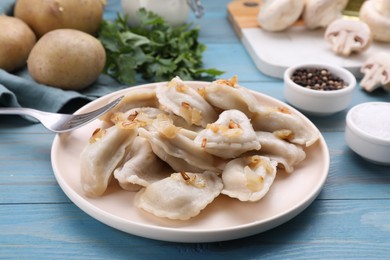 Photo of Delicious dumplings (varenyky) with potatoes and onion served on light blue wooden table