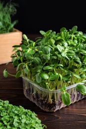 Photo of Fresh organic microgreens in containers on wooden table