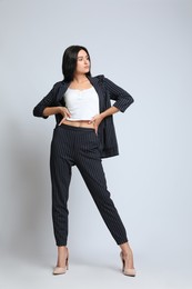 Photo of Full length portrait of beautiful woman in formal suit on light background. Business attire