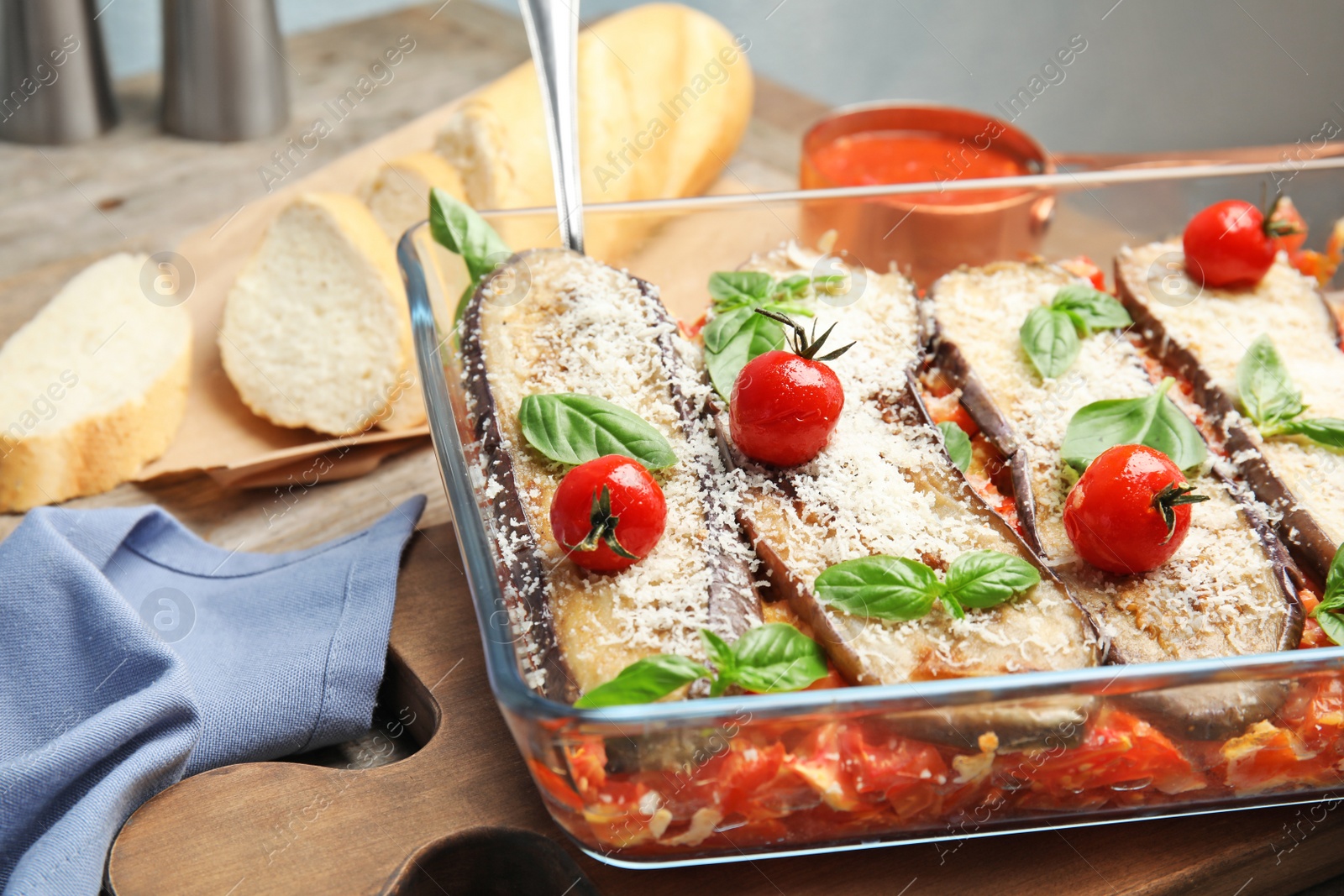 Photo of Baked eggplant with tomatoes, cheese and basil in dishware on table, closeup