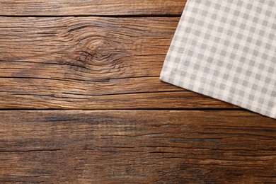 Photo of Beige checkered tablecloth on wooden table, top view. Space for text
