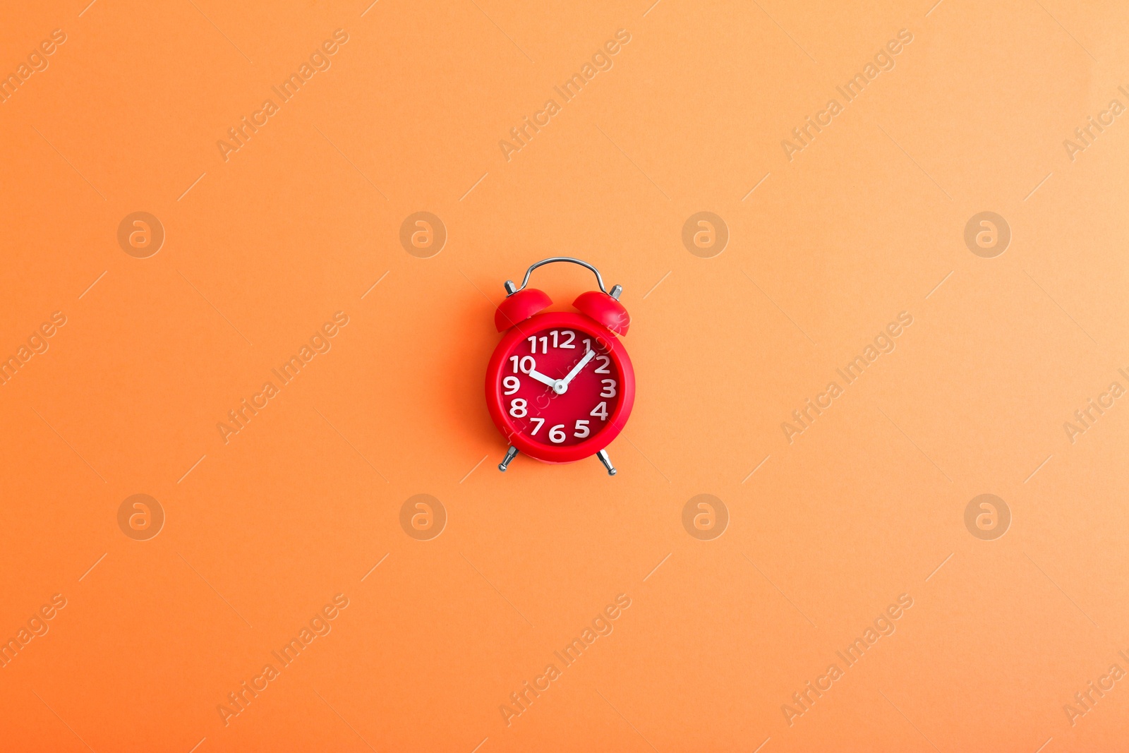 Photo of Modern alarm clock on orange background, top view