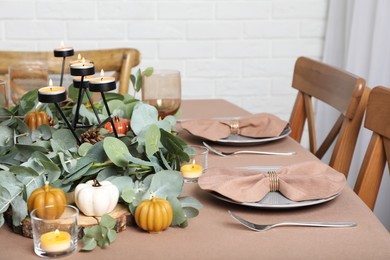 Photo of Autumn table setting with eucalyptus branches and pumpkins indoors