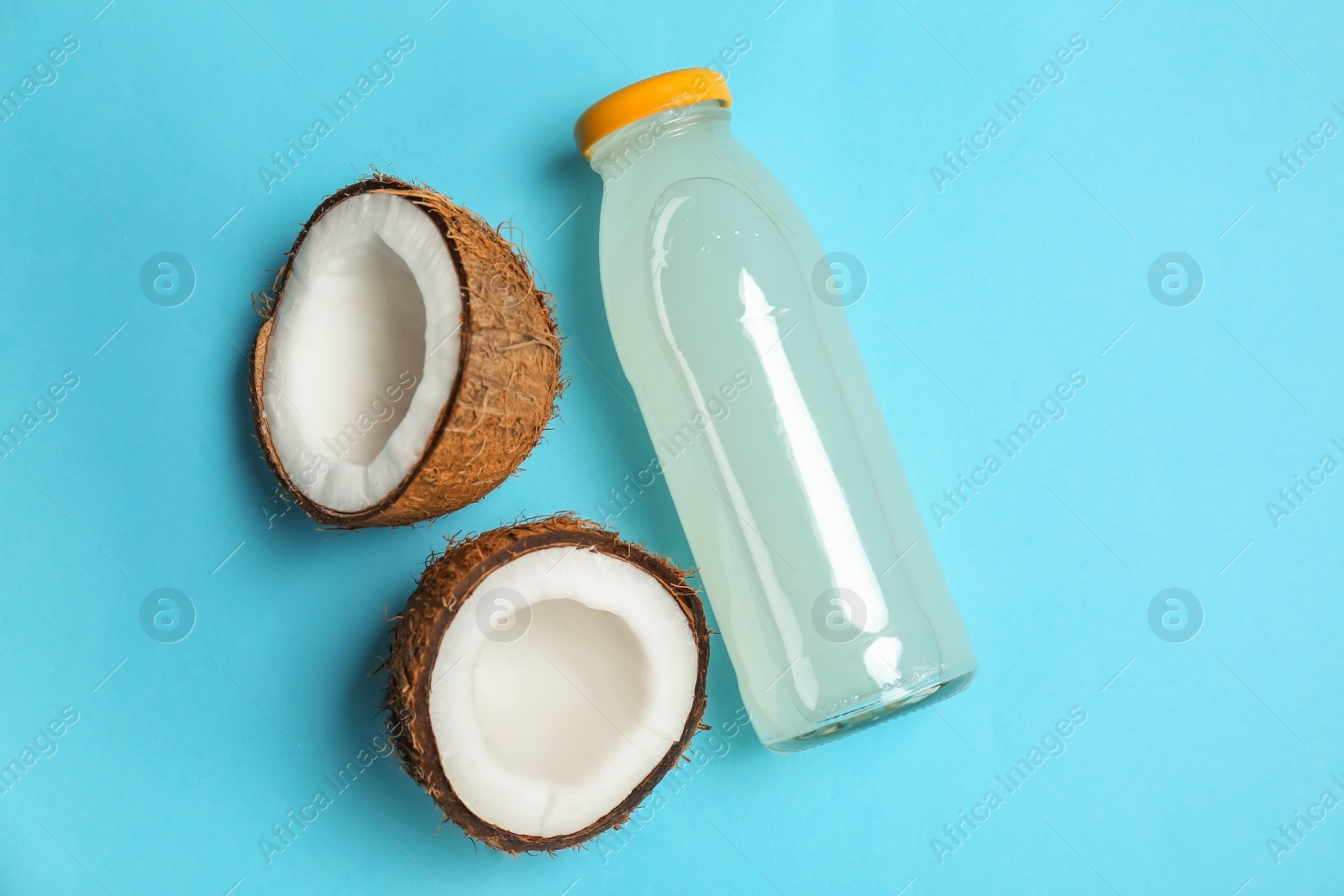 Photo of Bottle of coconut water and fresh nuts on color background