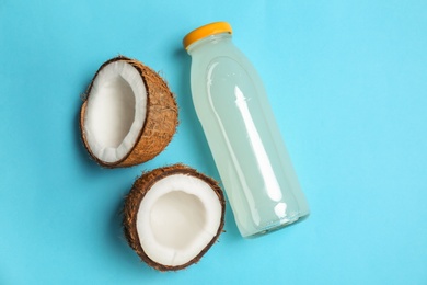 Bottle of coconut water and fresh nuts on color background