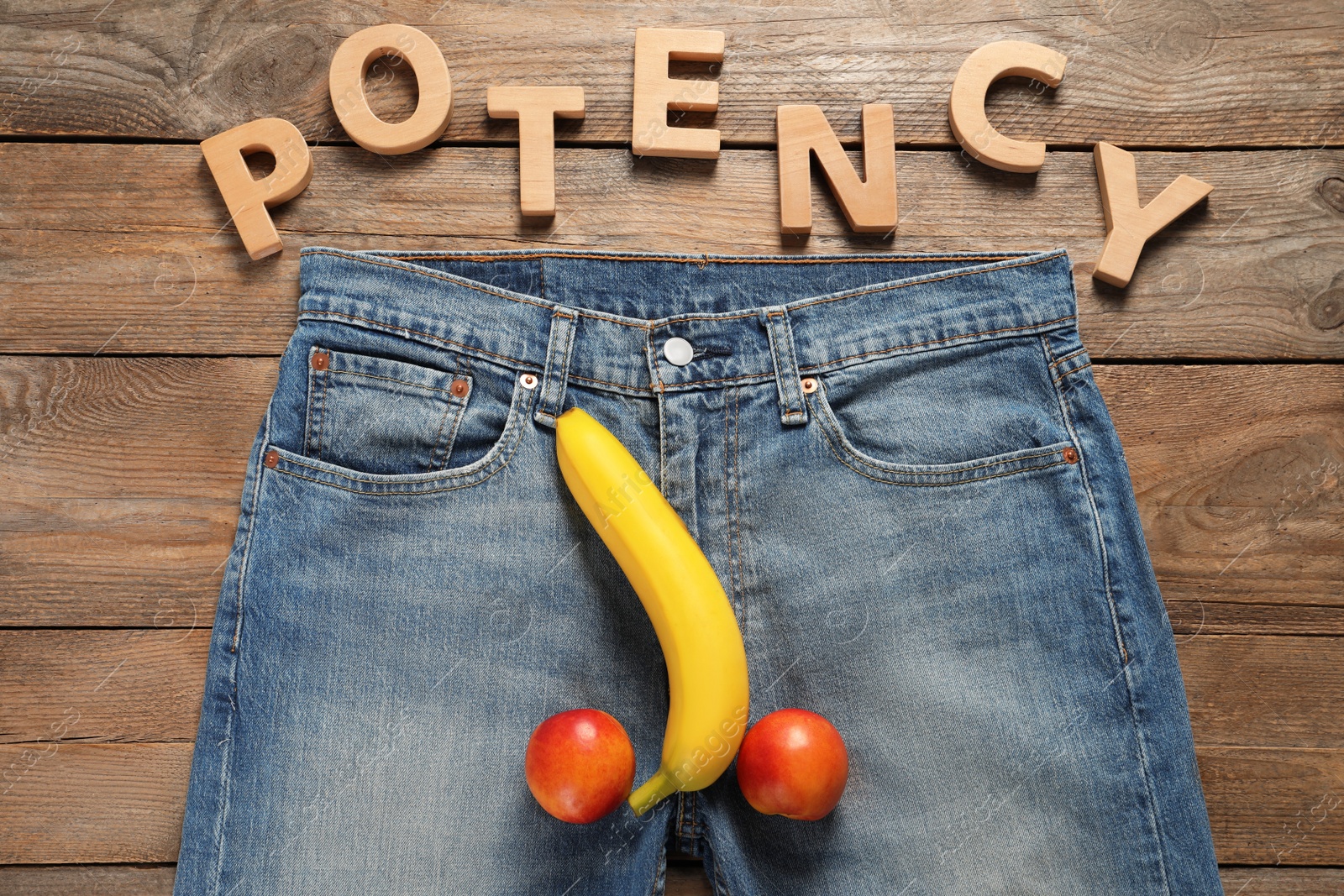 Photo of Men jeans with banana and nectarines symbolizing male genitals near word Potency on wooden table, flat lay