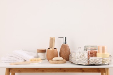 Photo of Different bath accessories and personal care products on table near white wall