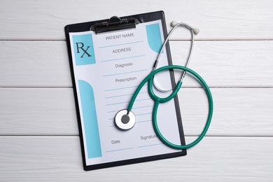 Photo of Clipboard with medical prescription form and stethoscope on white wooden table, flat lay