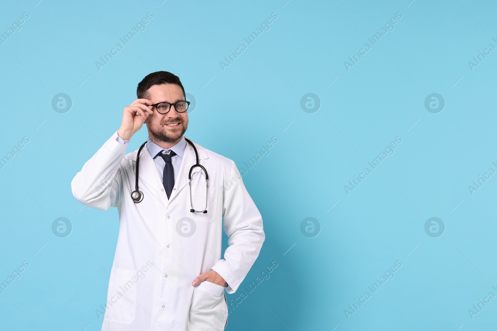 Photo of Smiling doctor on light blue background, space for text